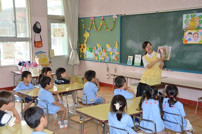 教室で先生が読む絵本に聞き入る園児たちの画像