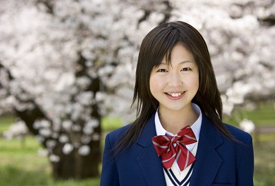 桜の木を背景に微笑む女子学生