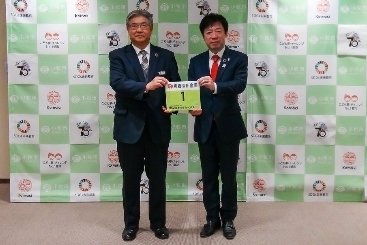 ナンバーカードを持つ東春信用金庫の神理事長と山下市長