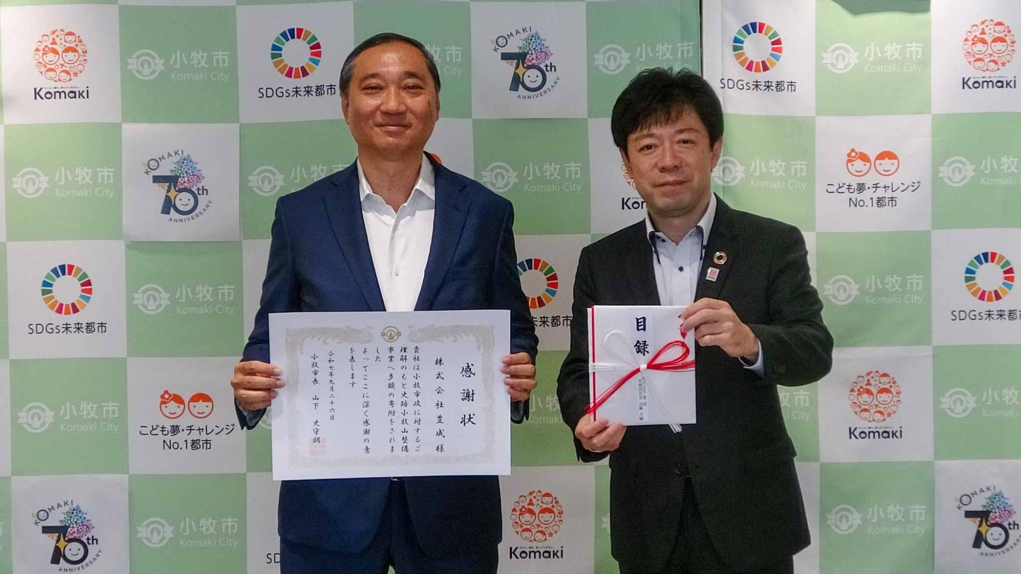 感謝状を持つ株式会社豊成の近藤取締役社長と、目録を持つ山下市長