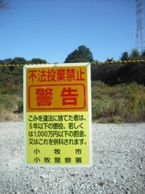 (写真)黄色の背景に赤字で大きく「警告」と記載されている、不法投棄禁止の啓発看板