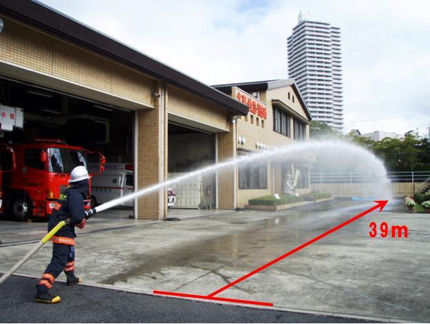 消防署の前で角度を付けて放水する隊員の写真