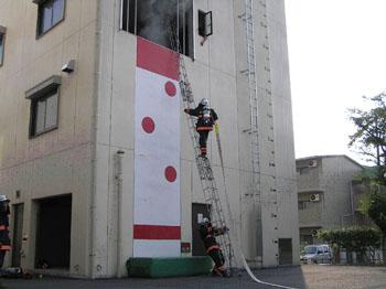 建物の3階へかかったはしごを登る隊員とはしごと支える隊員の写真
