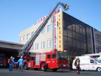 消防署の前ではしごを伸ばした消防車と救急車の写真