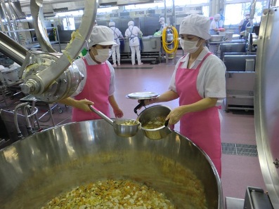 食物アレルギー対応食を鍋に入れる給食センター職員