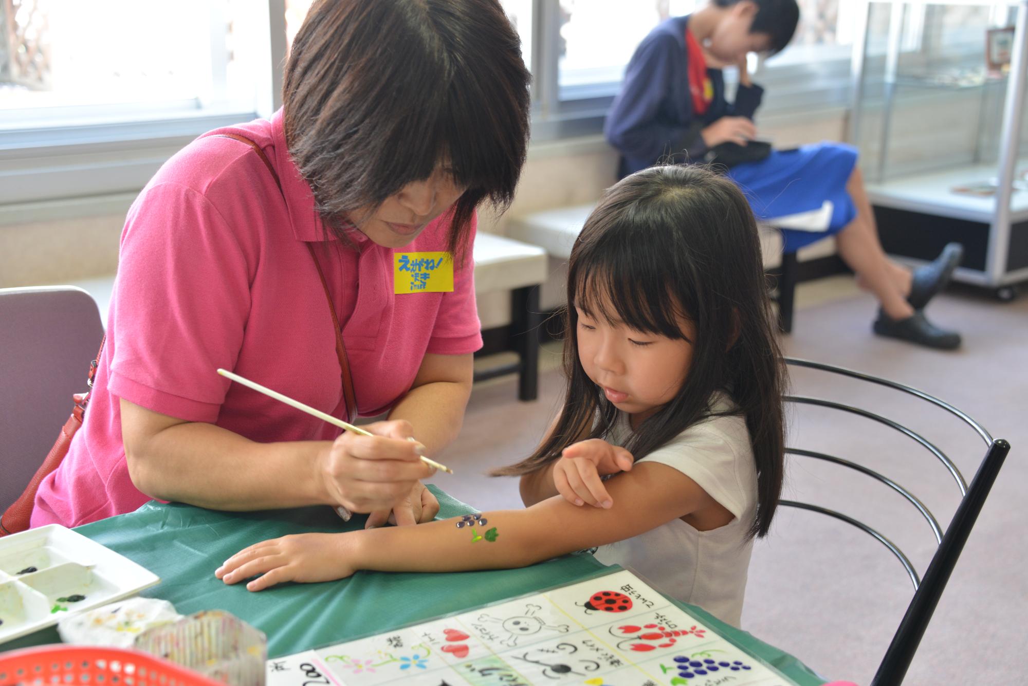 腕にペイントをしてもらっている子ども
